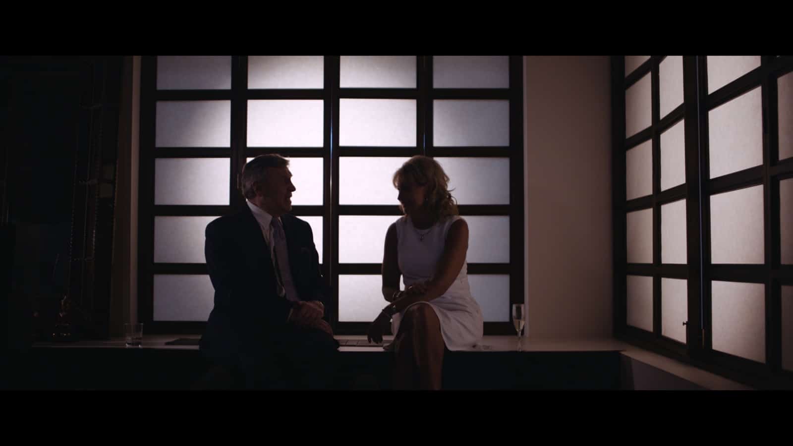 Man and woman talking to each other in semi darkness with glasses of alcohol next to them