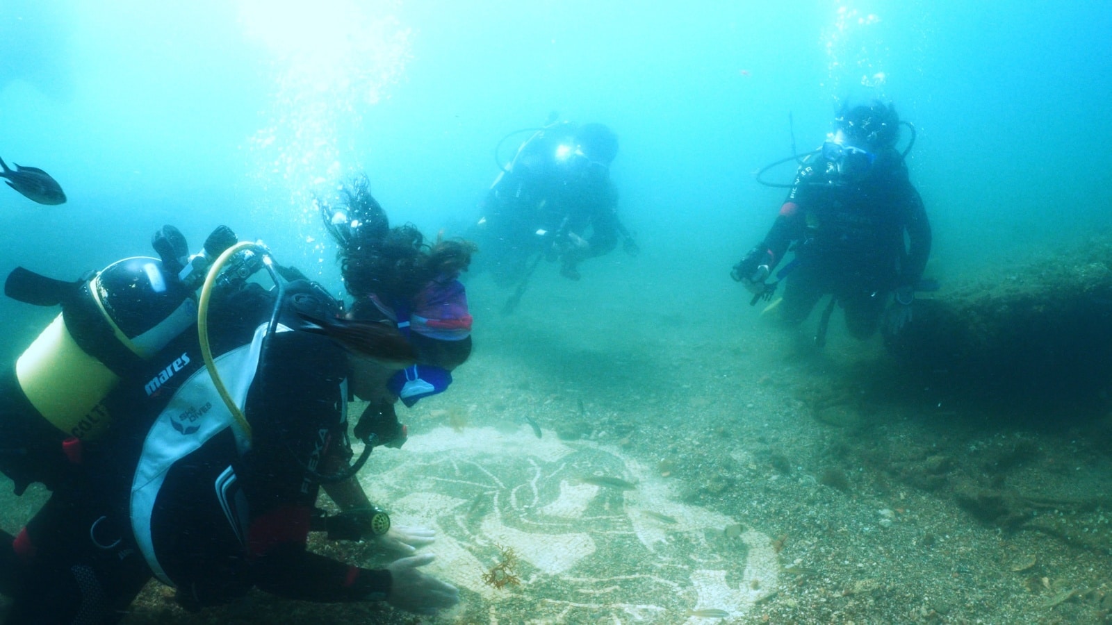 Three people scuba diving wearing gear