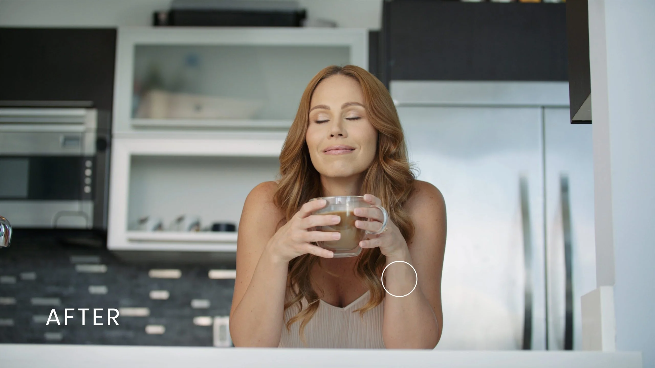 Welloff Woman with long hair posing for the camera with her eyes closed holding a cup of coffee in the kitchen