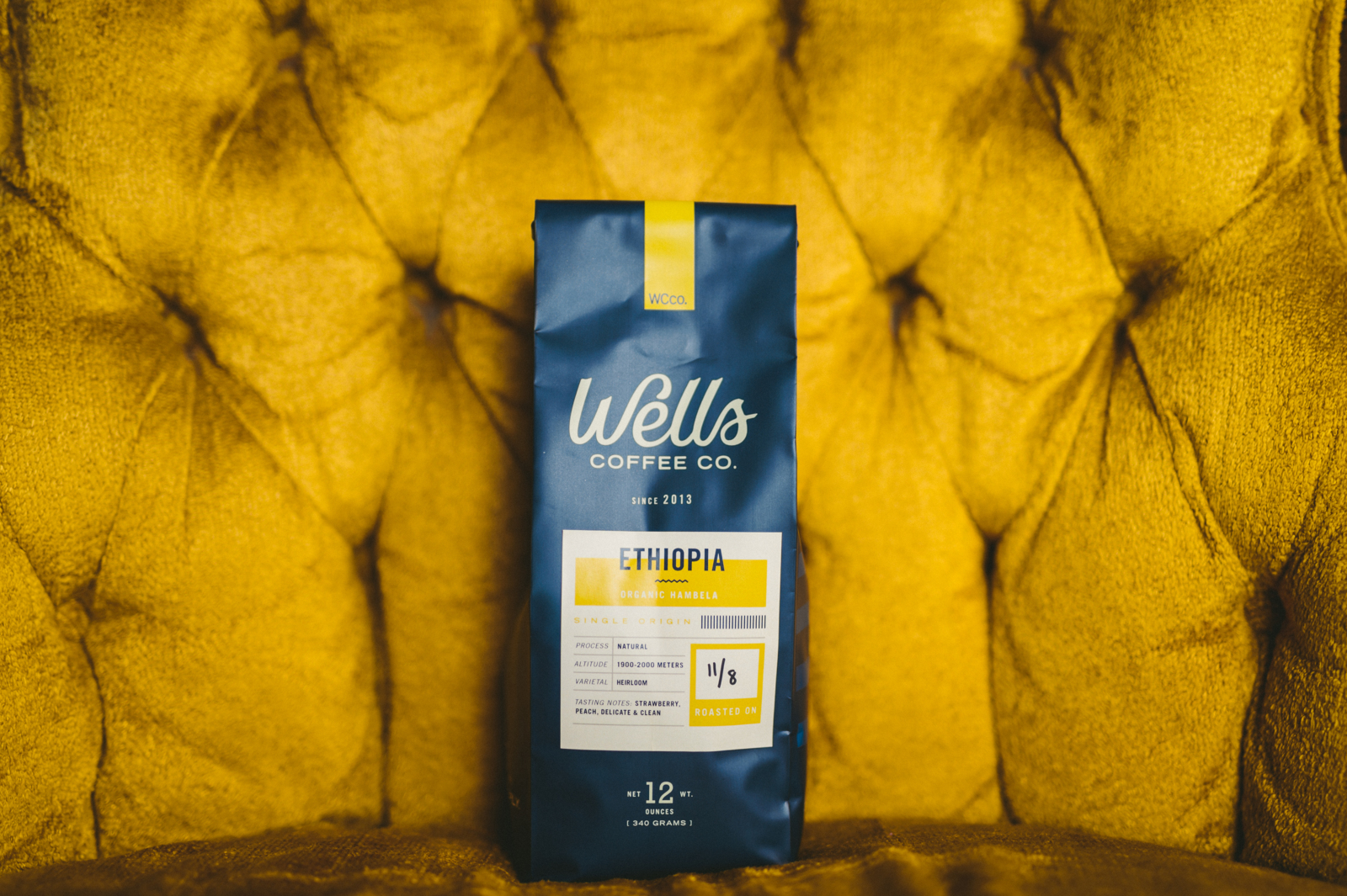 IU C&I Studios Page and Post How to Update Your Logo Design without Losing Brand Recognition Bag of Ethiopia version of coffee from Wells Coffee Co on display on mustard colored plush chair