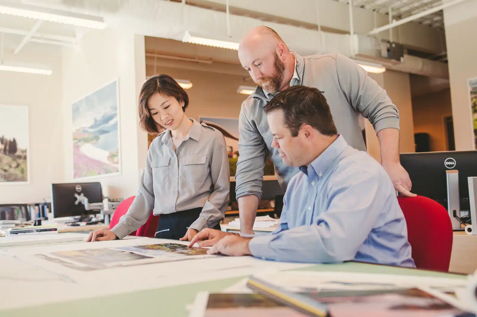 Keyword: Brand Identity .The Importance of Pre Production Planning in Corporate Video Production Two men and a woman looking over drafts on a table. Pre-Production Process