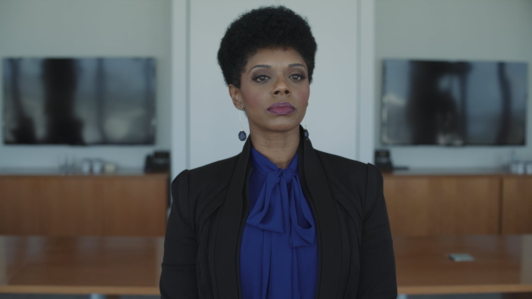 Headshot of woman with short black hair wearing a dark blue dress shirt and black dress jacket posing for the camera