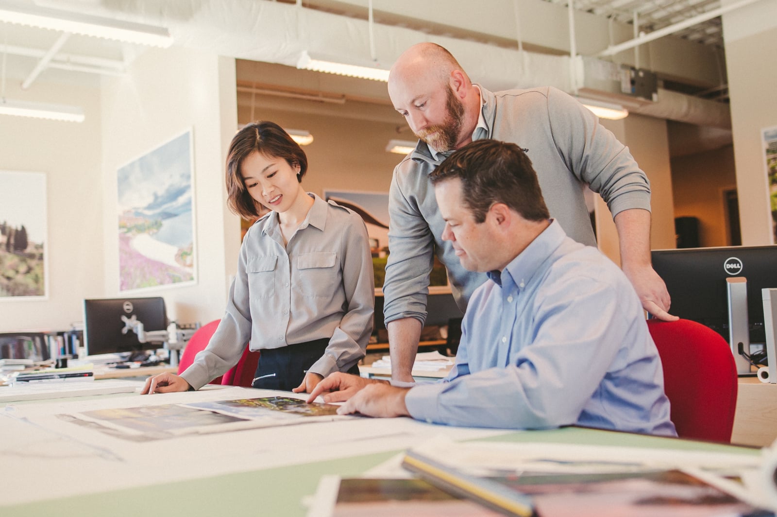 Keyword: Brand Identity .The Importance of Pre Production Planning in Corporate Video Production Two men and a woman looking over drafts on a table. Pre-Production Process