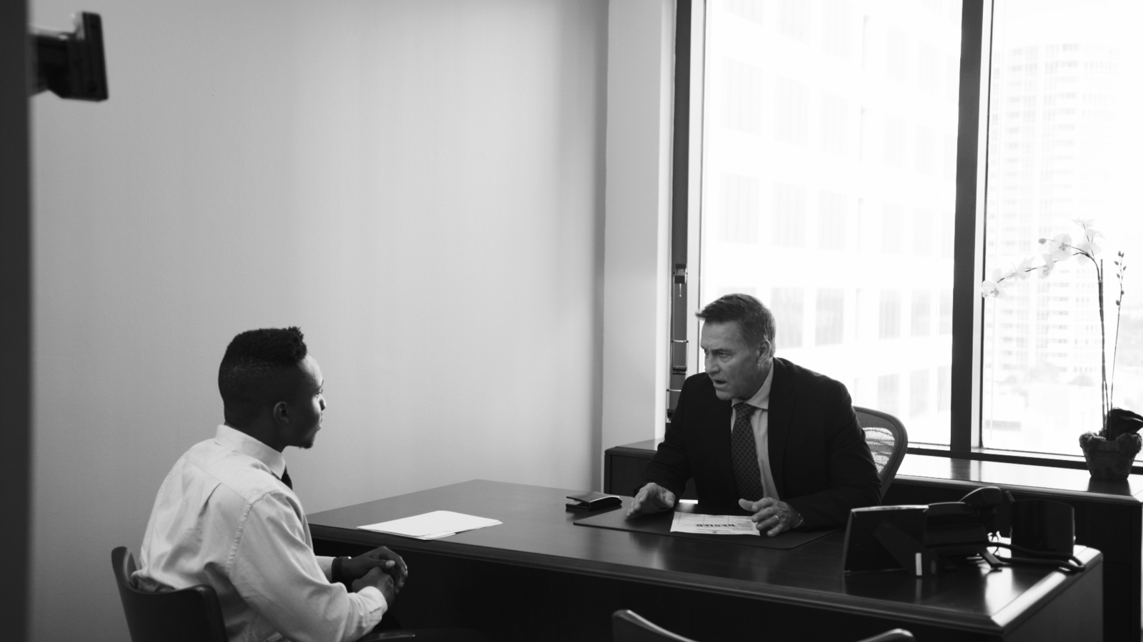 IU C&I Studios Page and Post The Different Types of Corporate Videos and When to Use Them Black and white of man talking to young African American man in an office