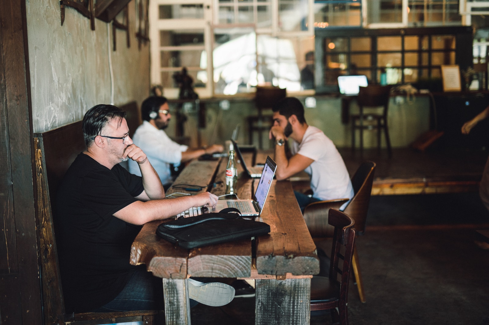 Side profile of three men working on laptops at a table
