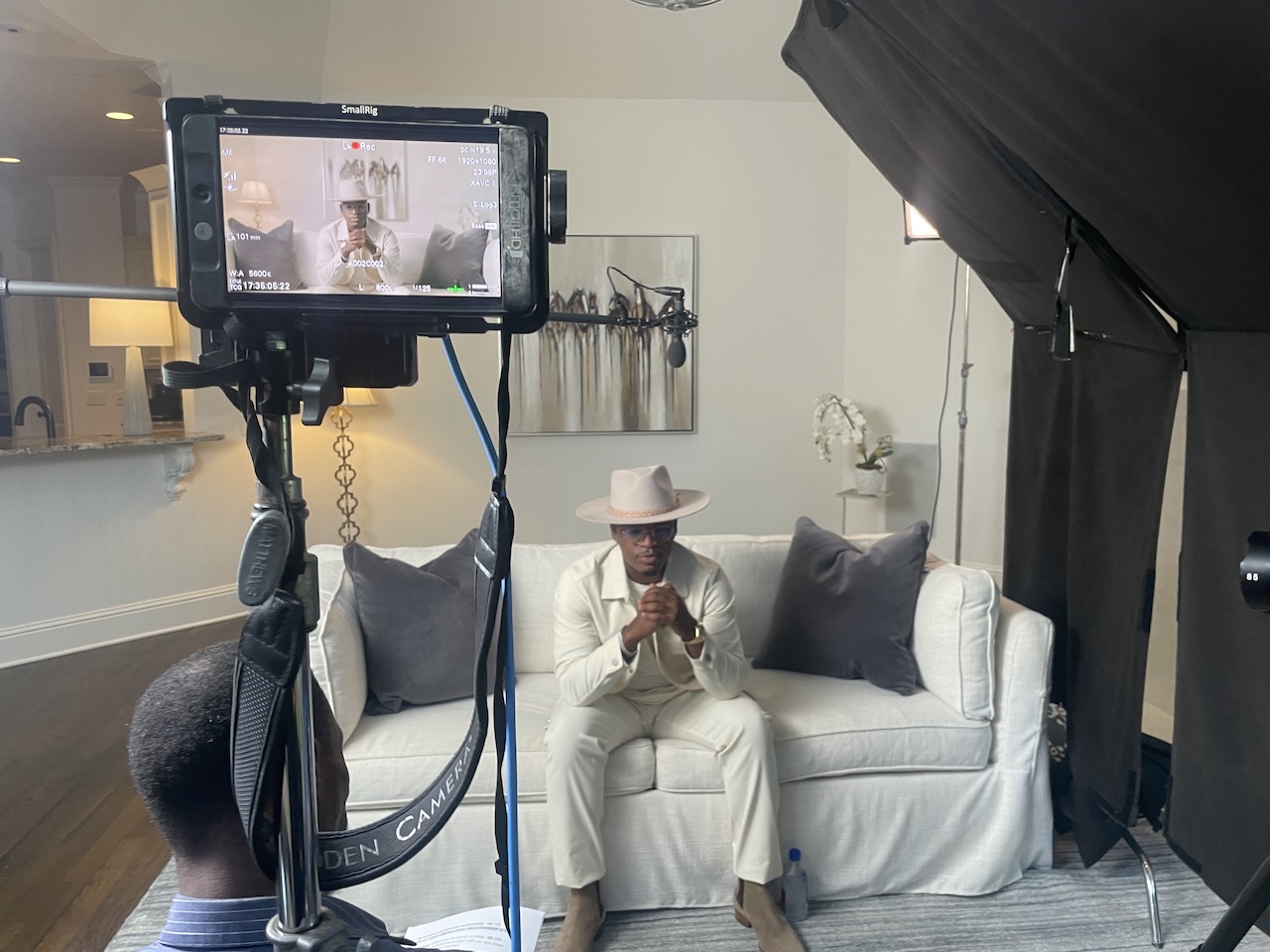 BlackPopBTS Neyo by CI Studios On set with him in a white suit sitting on a white sofa with closeup of video monitor in the foreground