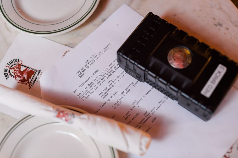 IU CI Studios services feature film production Closeup of red brick equipment on a script next to a plate and silverware wrapped in a napkin