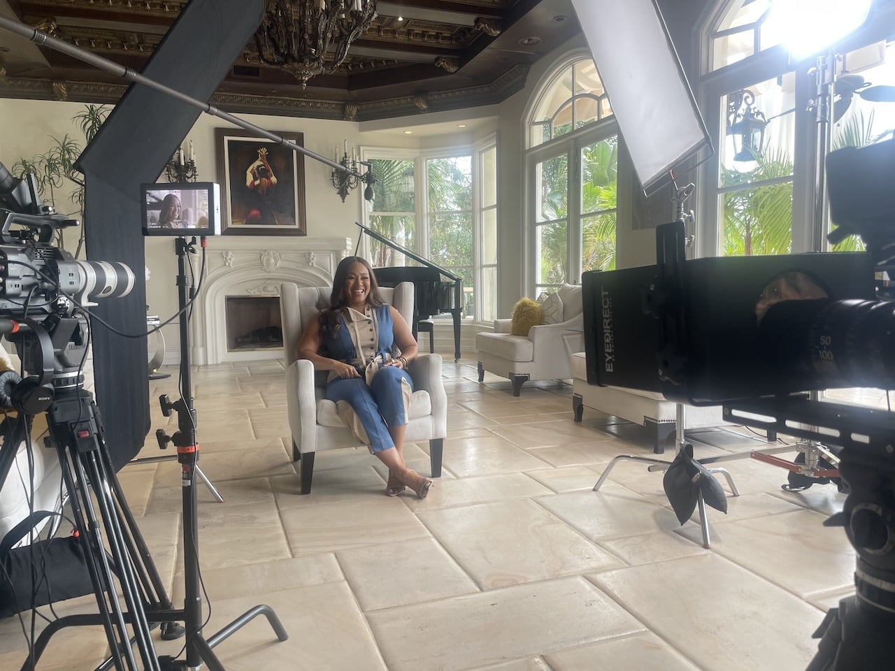 On set with Erika Campbell smiling for the camera, crew and equipment