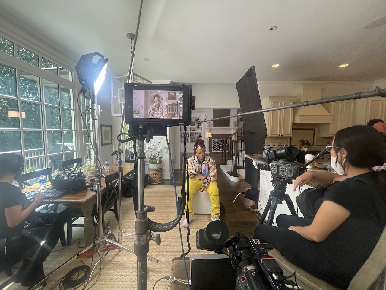 DaBrat on set with her being filmed by a female video camera operator surrounded by equipment and other crew members