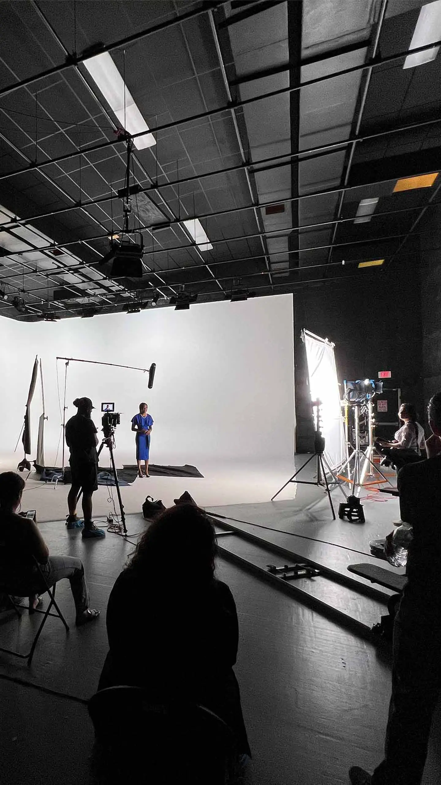 Video Producer Support 1 Production crew shooting footage in a warehouse with a large cycloramic wall in background