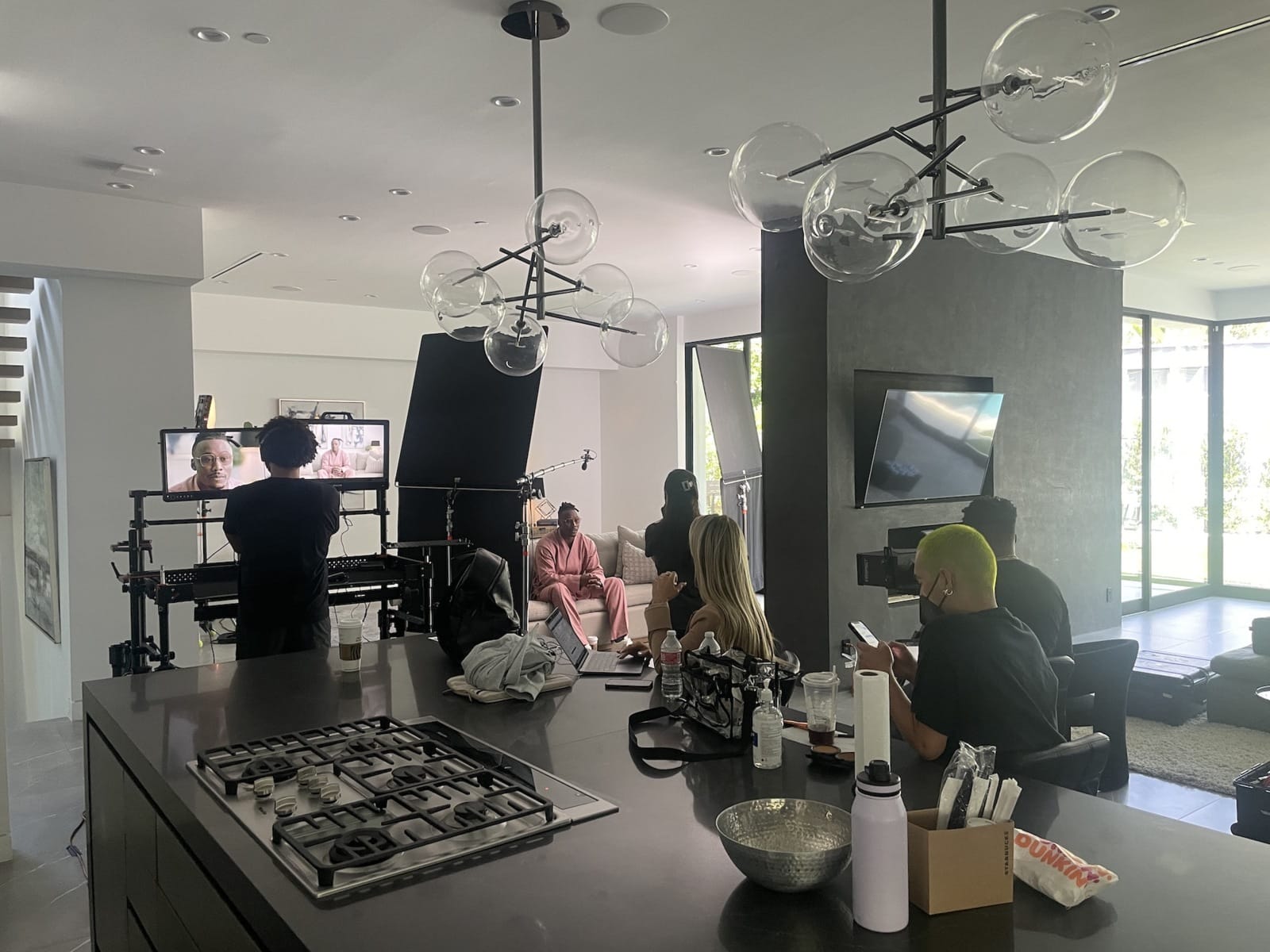 Crew on set with African American man in pink suit sitting on a couch