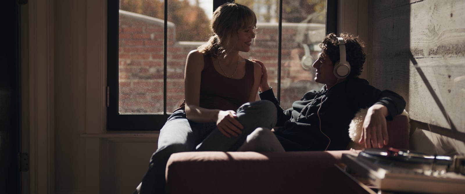Woman sitting near man wearing white headphones on a chair