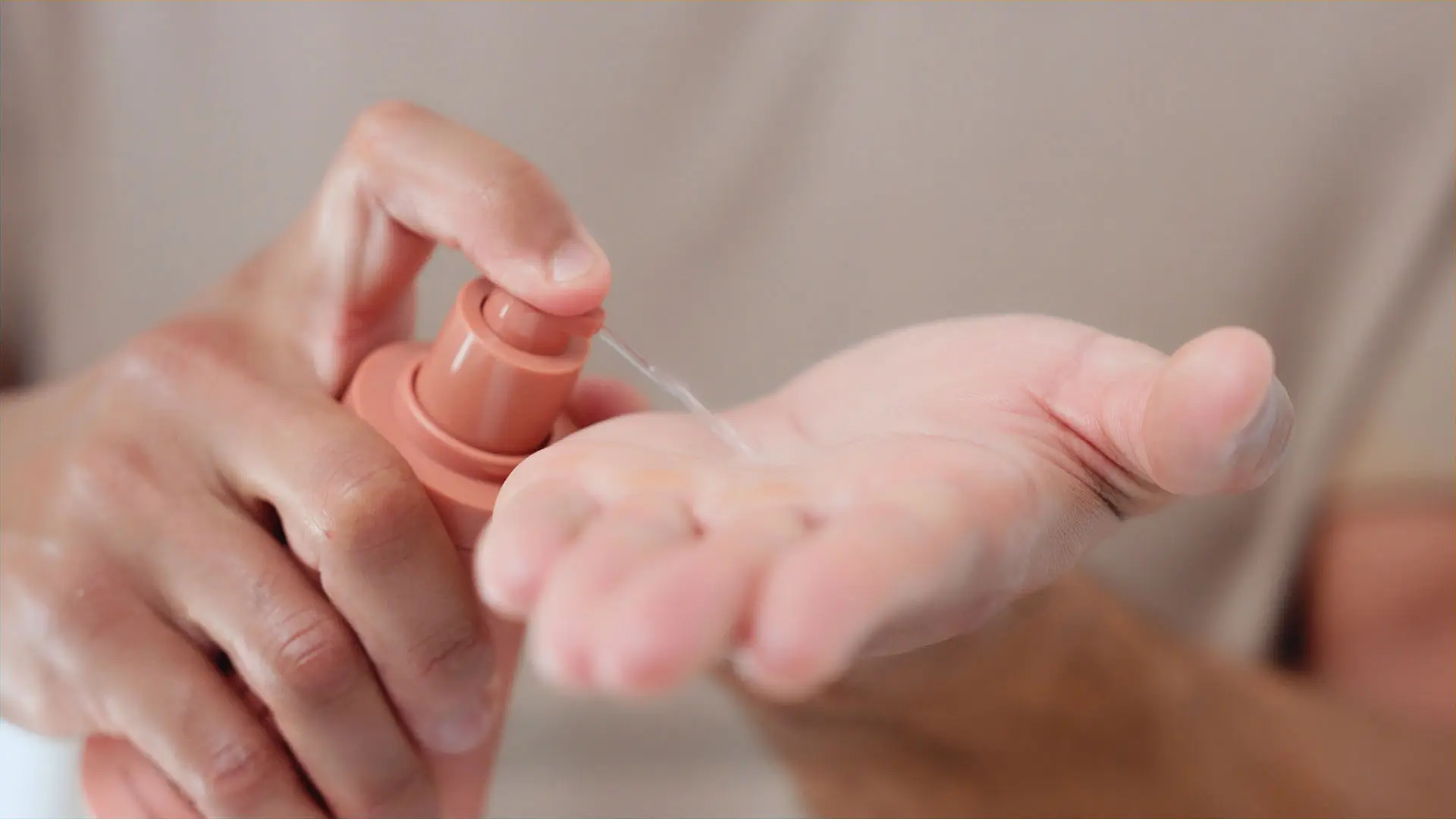 Closeup of liquid being squirted on hand from pink bottle