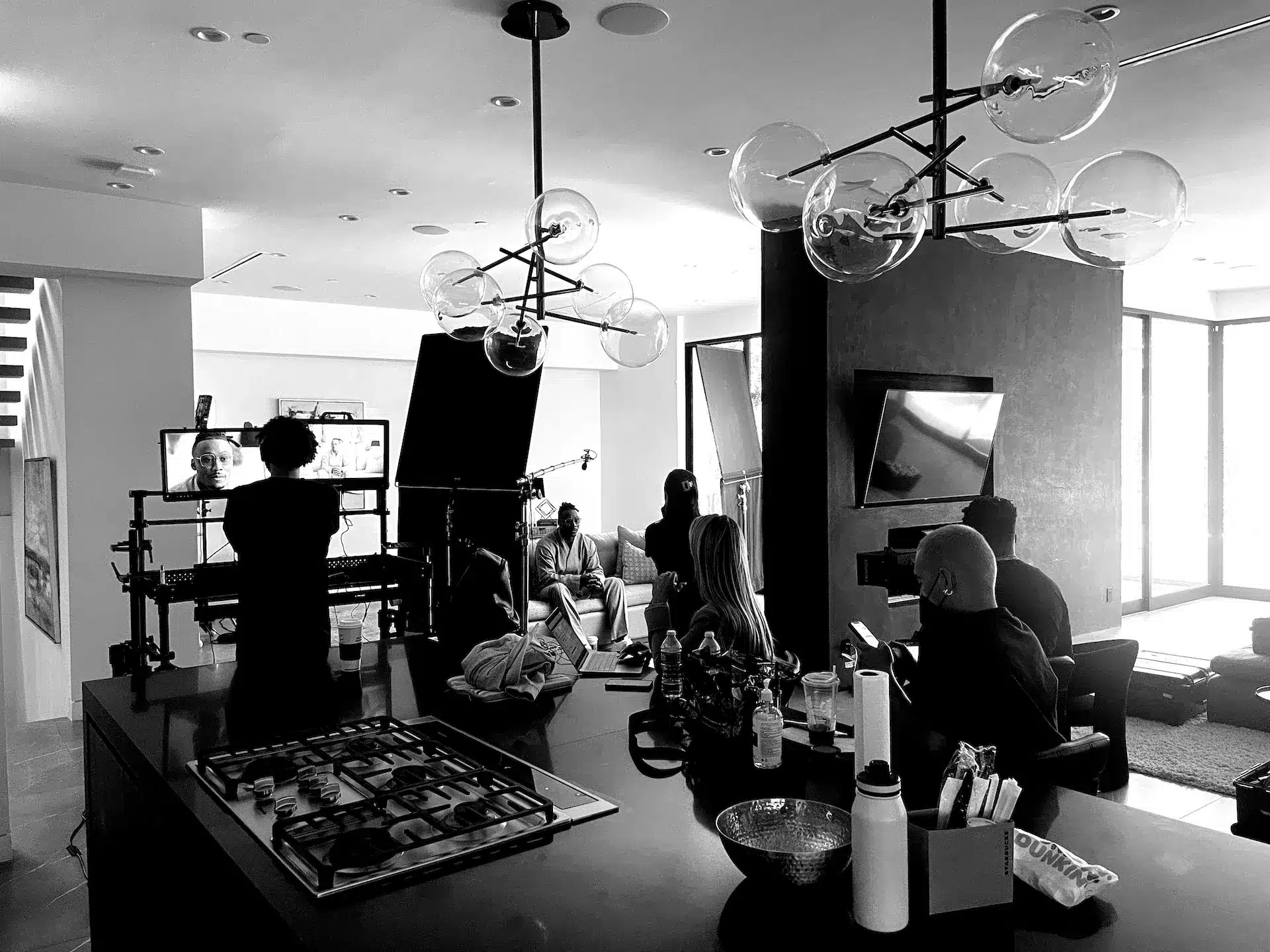 Brandon Marsall sitting on a set surrounded by crew and equipment black and white