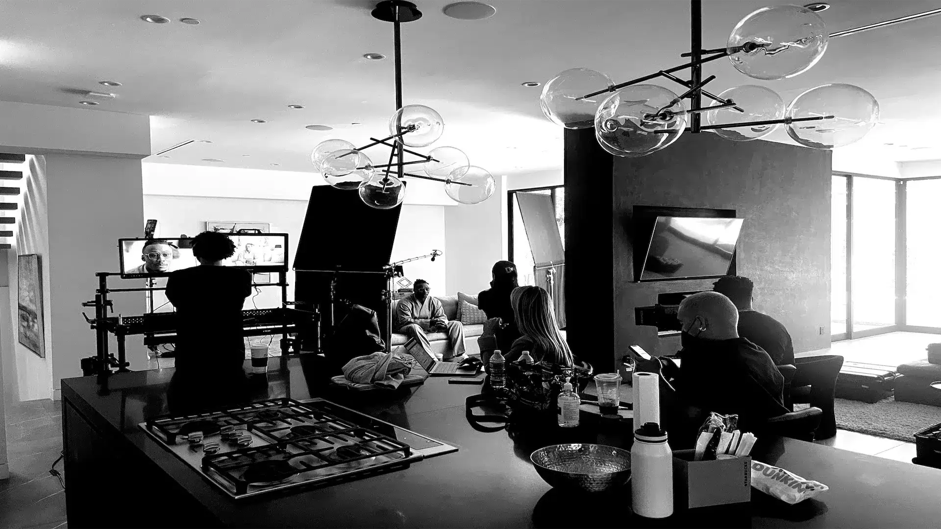 Brandon Marsall sitting on a set surrounded by crew and equipment black and white