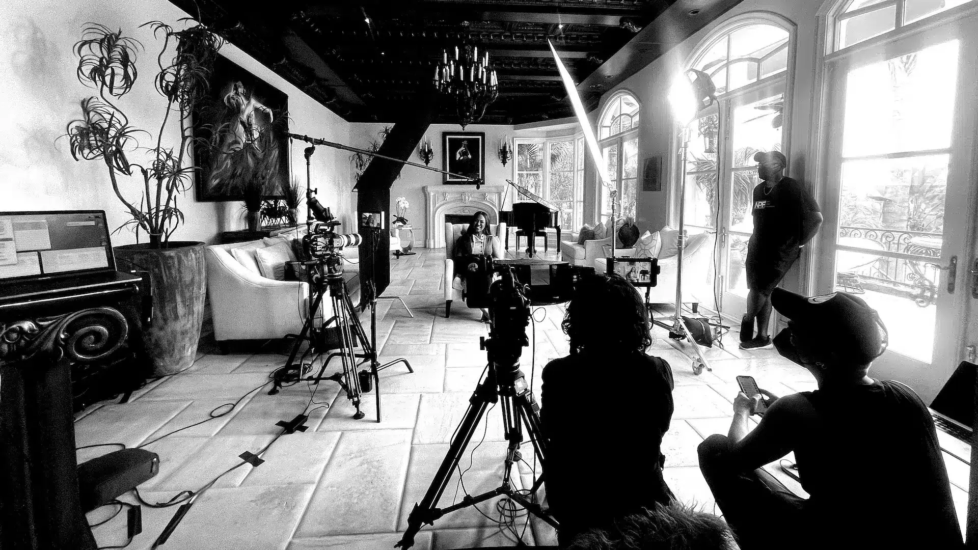 Erika Campbell sitting on a chair smiling with crew and equipment around