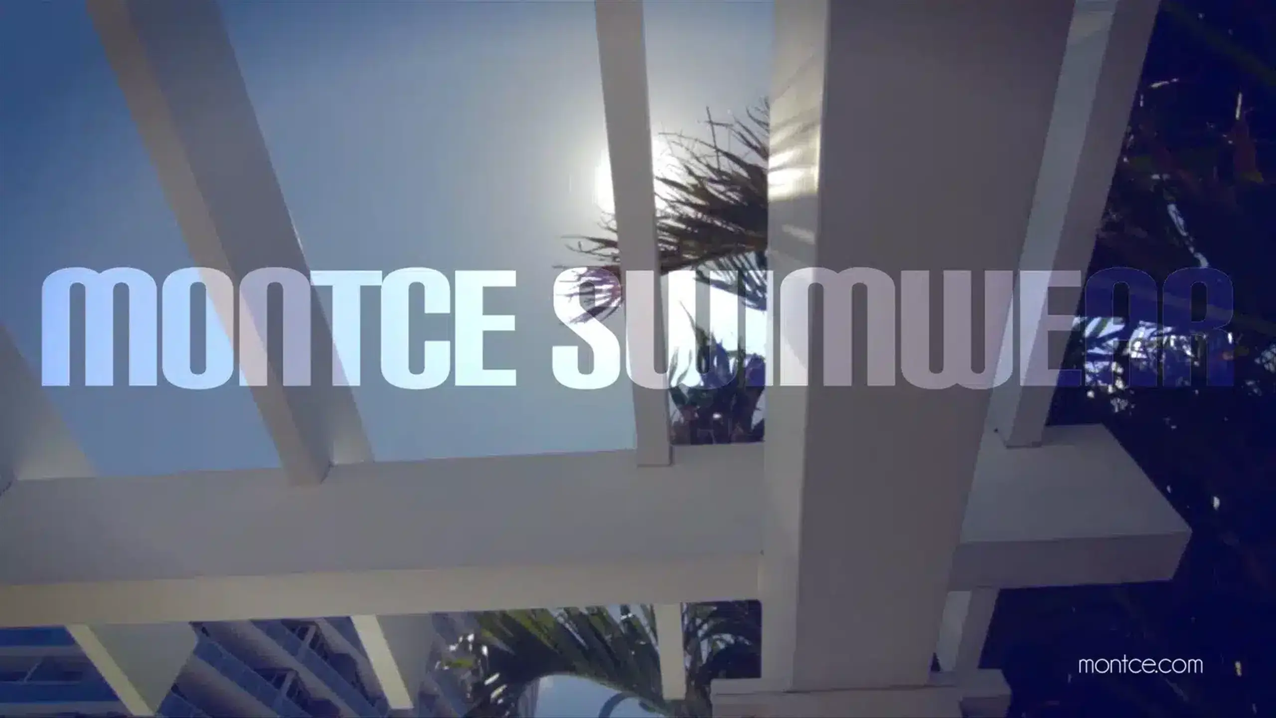 White Montce Swimwear logo on backdrop of building structure