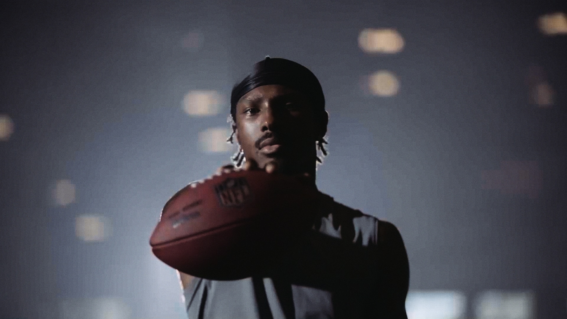 NFL player Mecole Hardman Jr. holding a football in front on him with one arm.