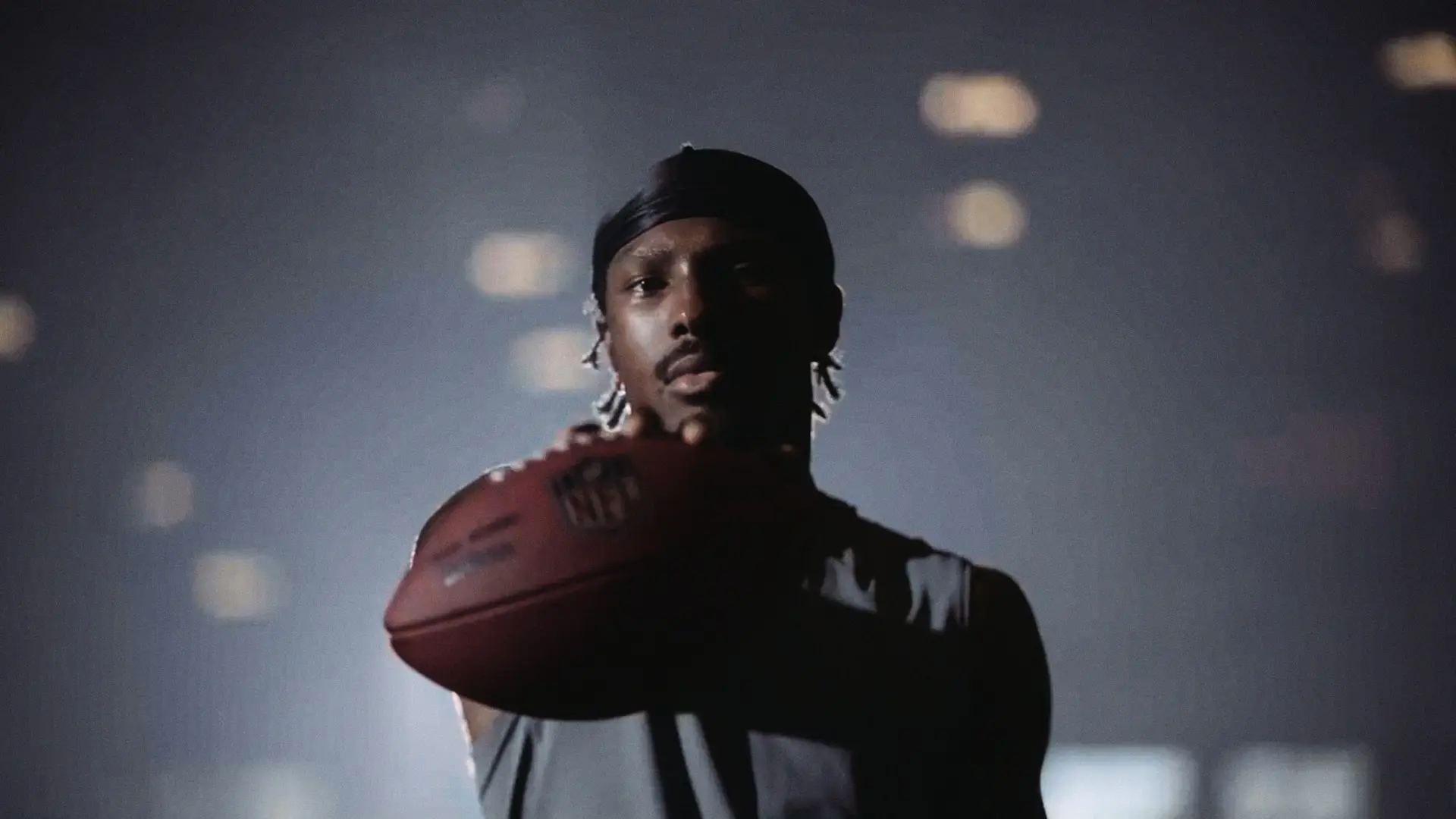 NFL 17 NFL player Mecole Hardman Jr. holding a football in front on him with one arm.