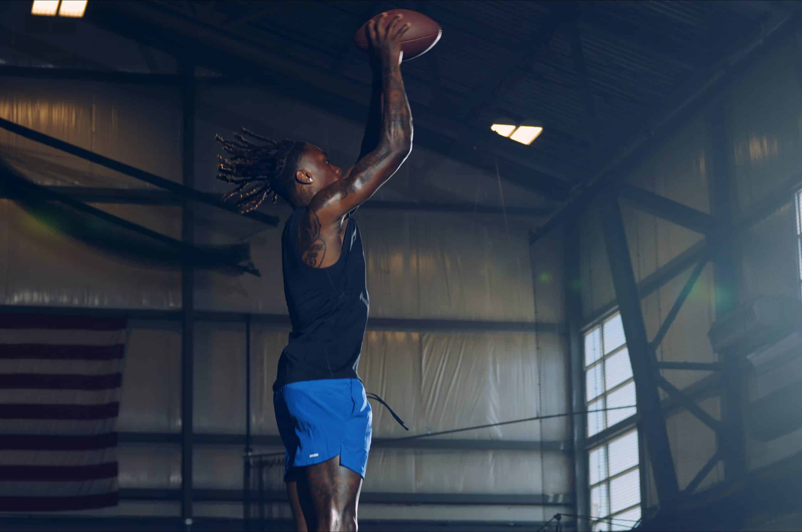 NFL player Xavier Worthy shooting a football like a basketball