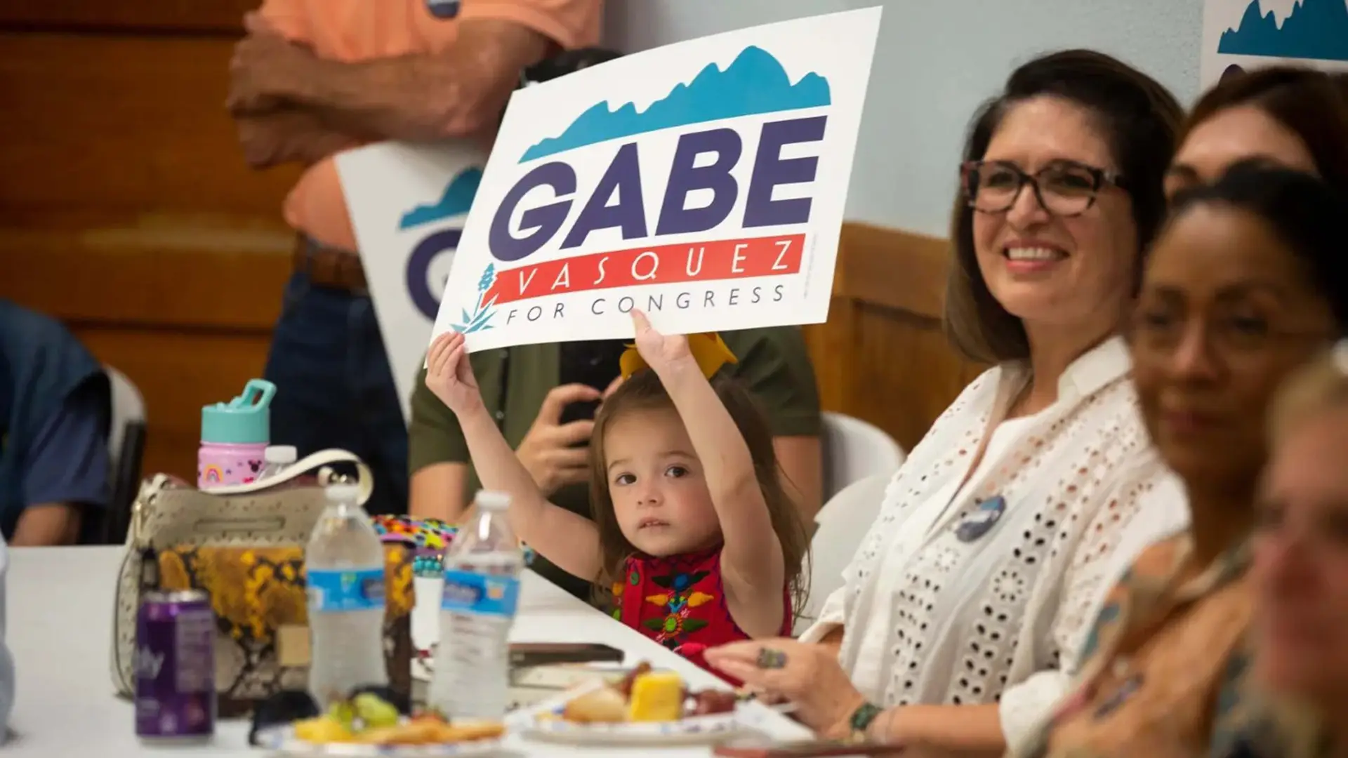 Gabe Vasquez 6 Little girl holding Gabe Vasquez placard above her head with people around her