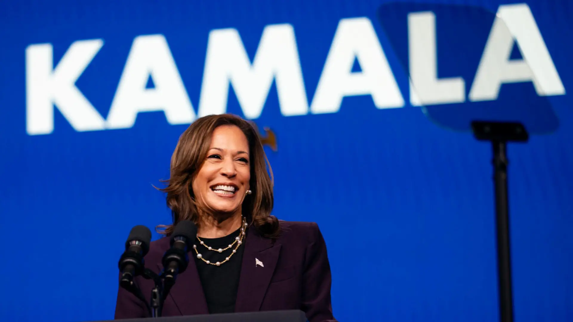 Kamala Harris 13 Kamala Harris smiling behind podium with name in background