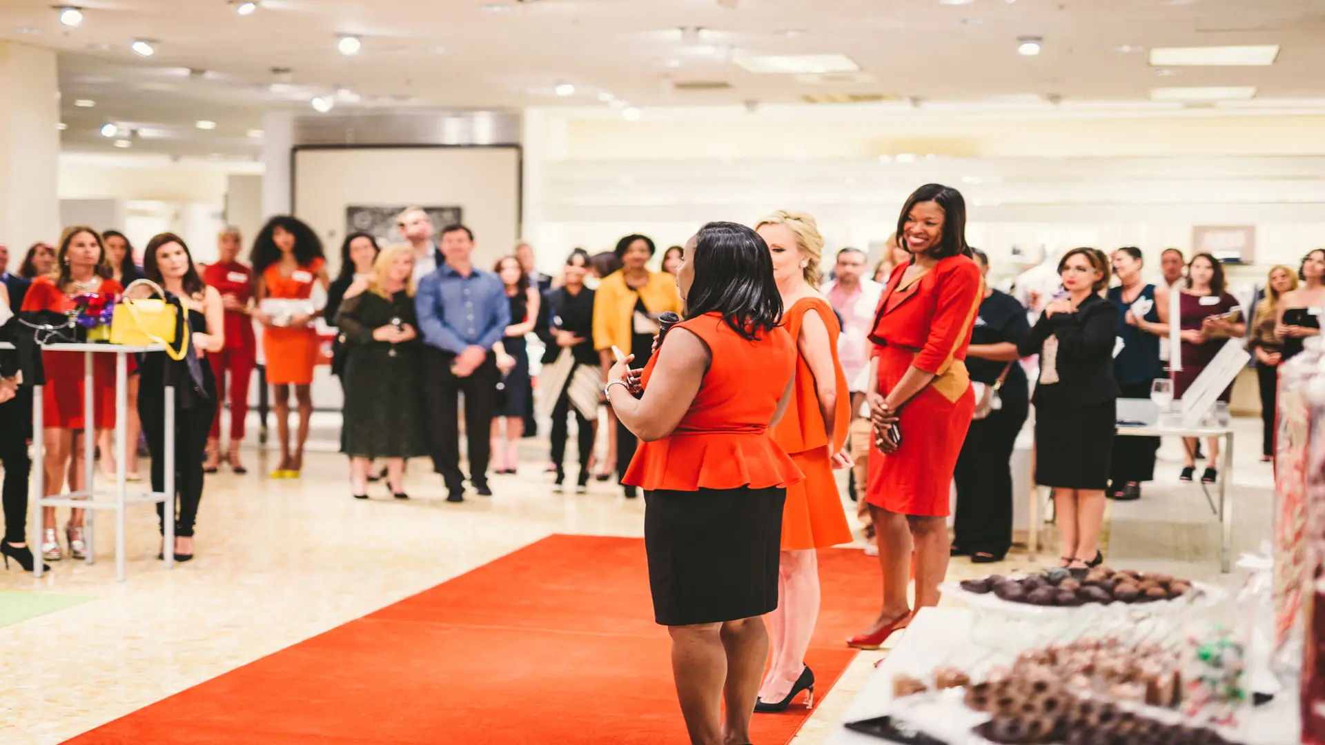 Neiman Marcus 11 Side profile of woman dressed in red holding microphone with two other women next to her
