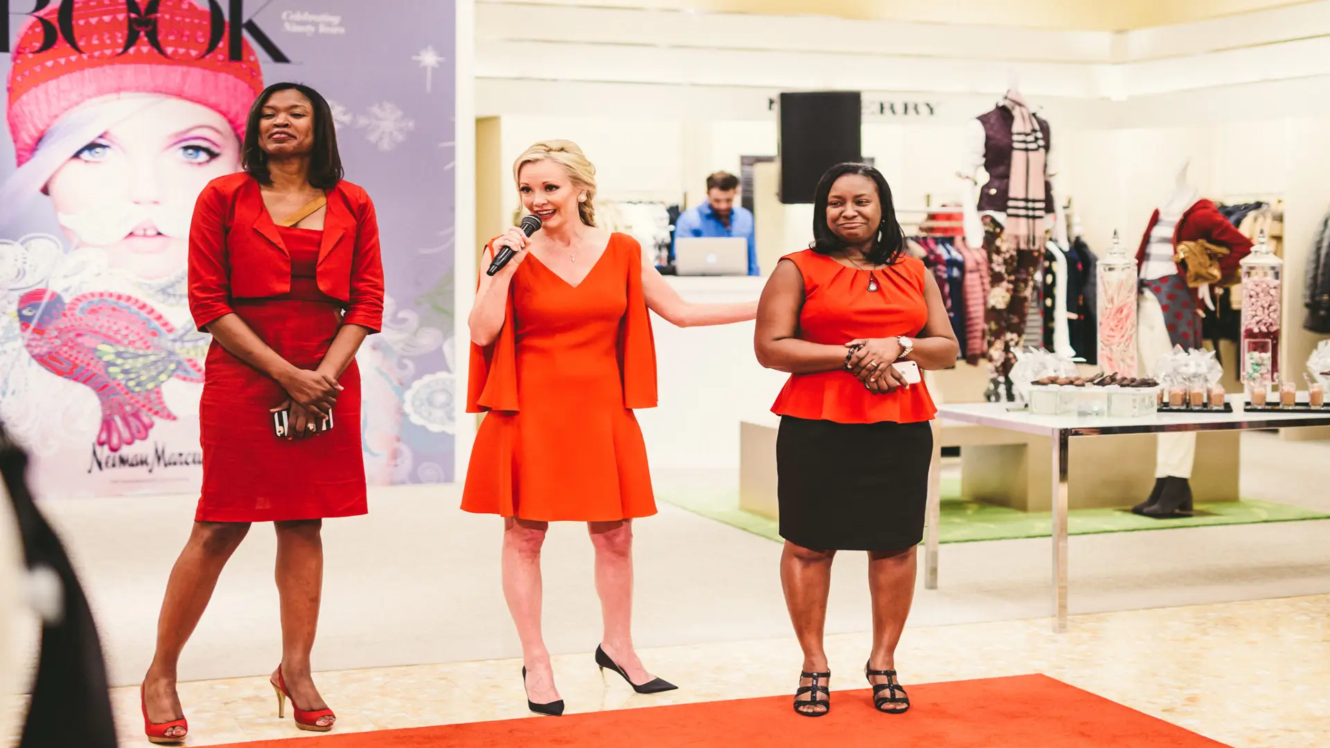 Neiman Marcus 9 Woman dressed in red holding microphone with two other women next to her