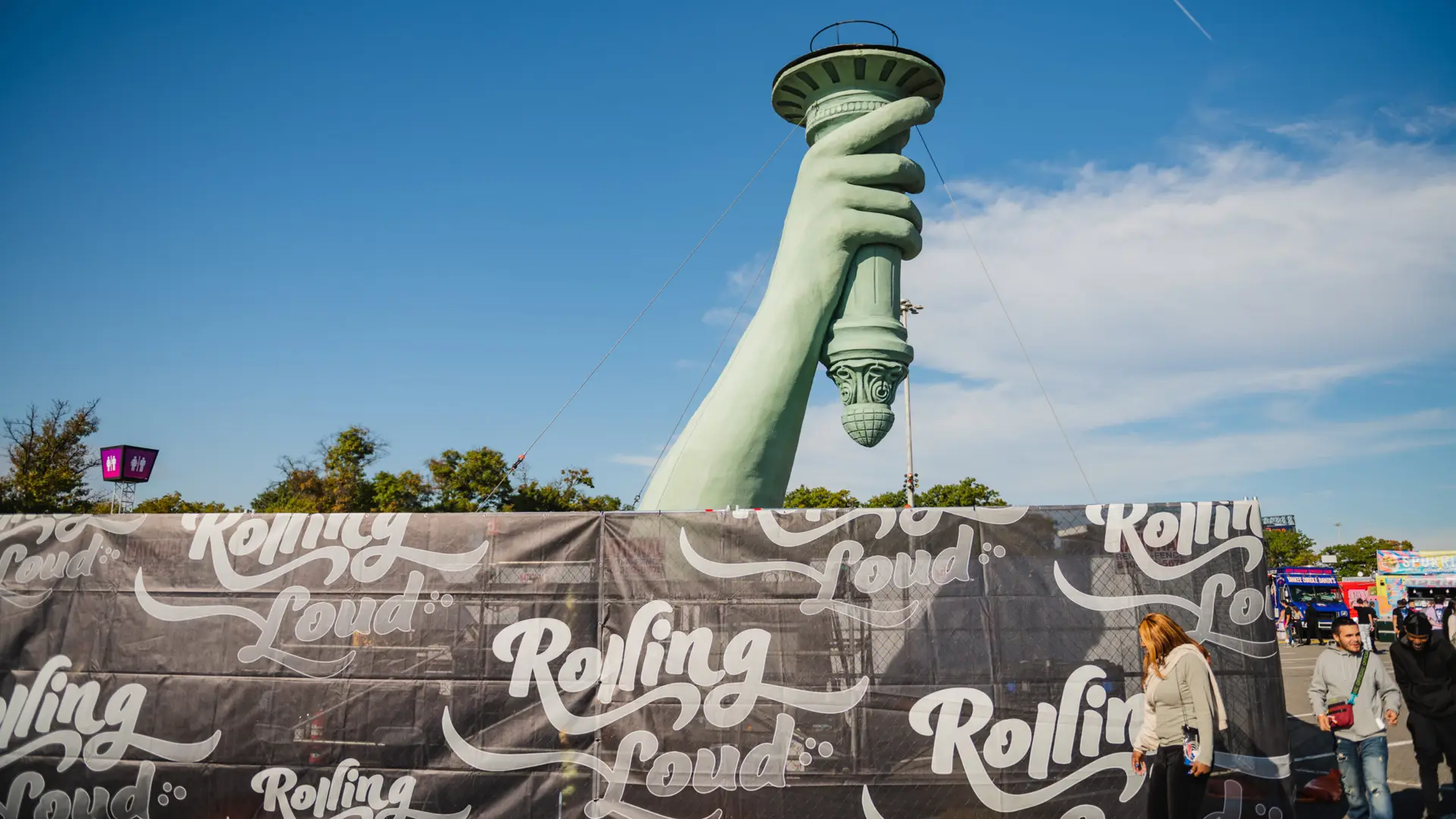 Rolling Loud 24 Upper part of Statue of Liberty arm and hand with torch behind wall with logo