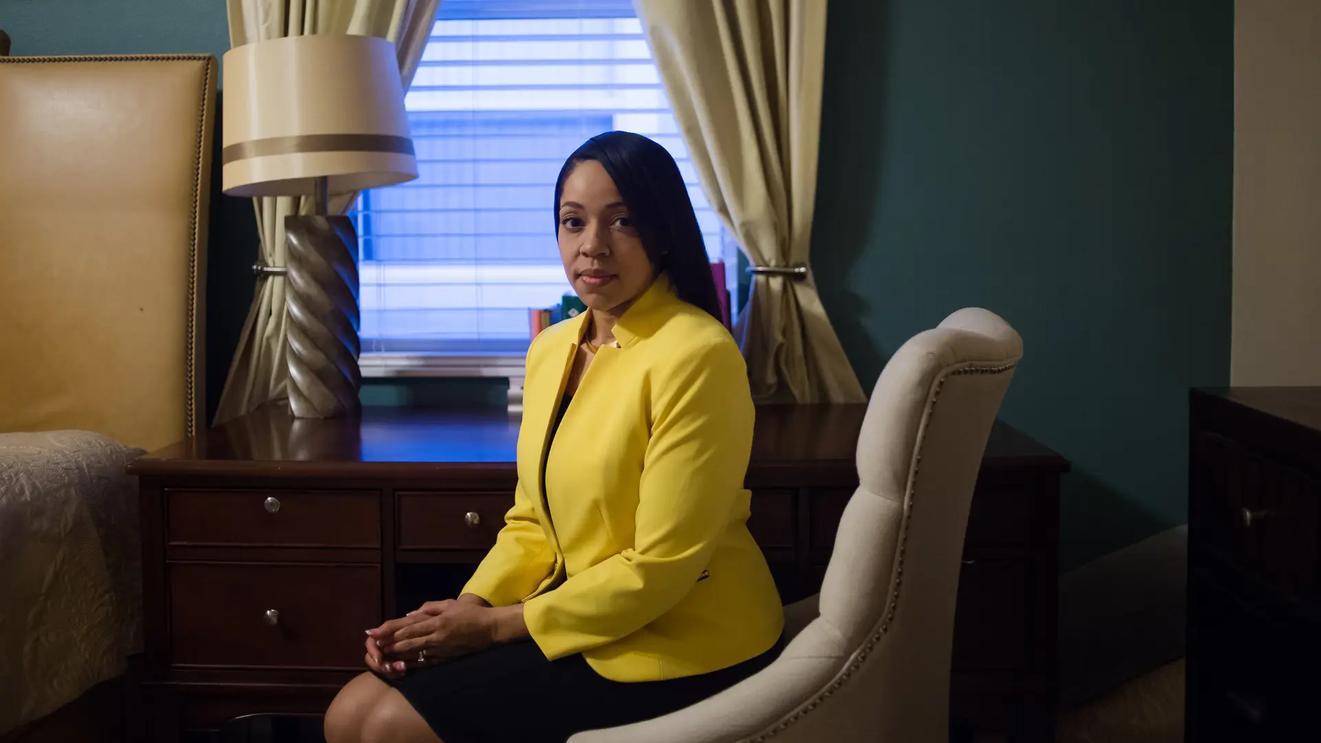 Aramis Ayala 9 Side profile of Aramis Ayala seated wearing a yellow dress shirt and black skirt