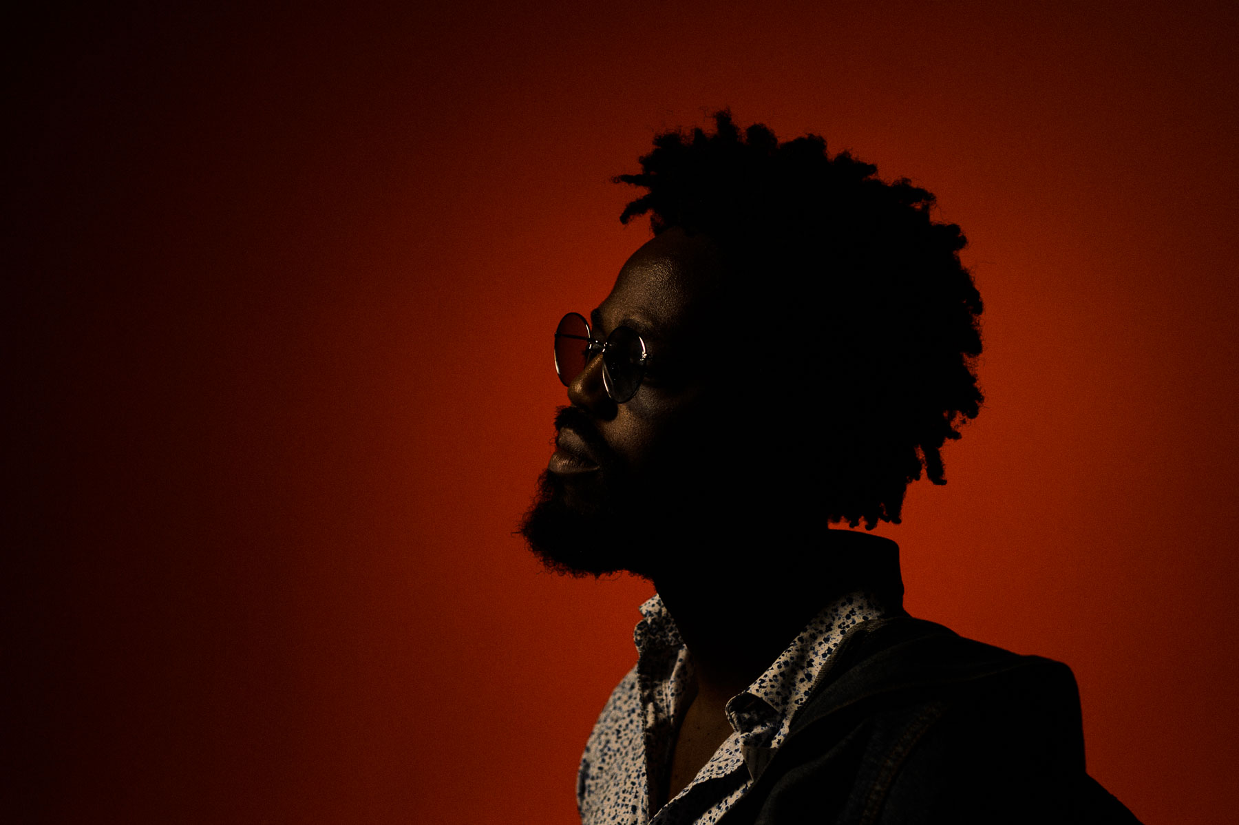 Lighting 5 Profile portrait held in near silhouette against a red wall with a thin edge of light