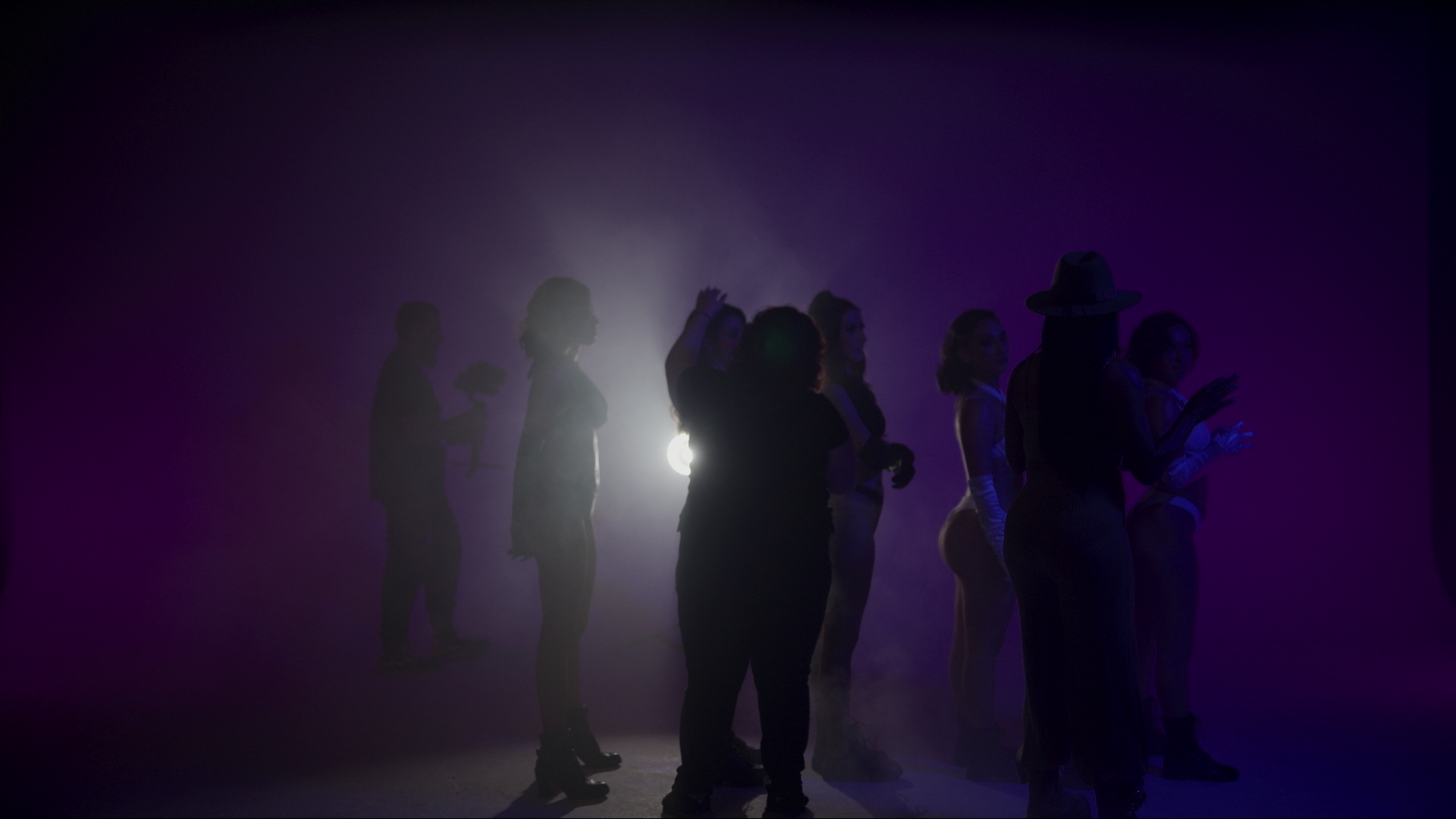 Dance video production ensemble in silhouette behind a single backlight