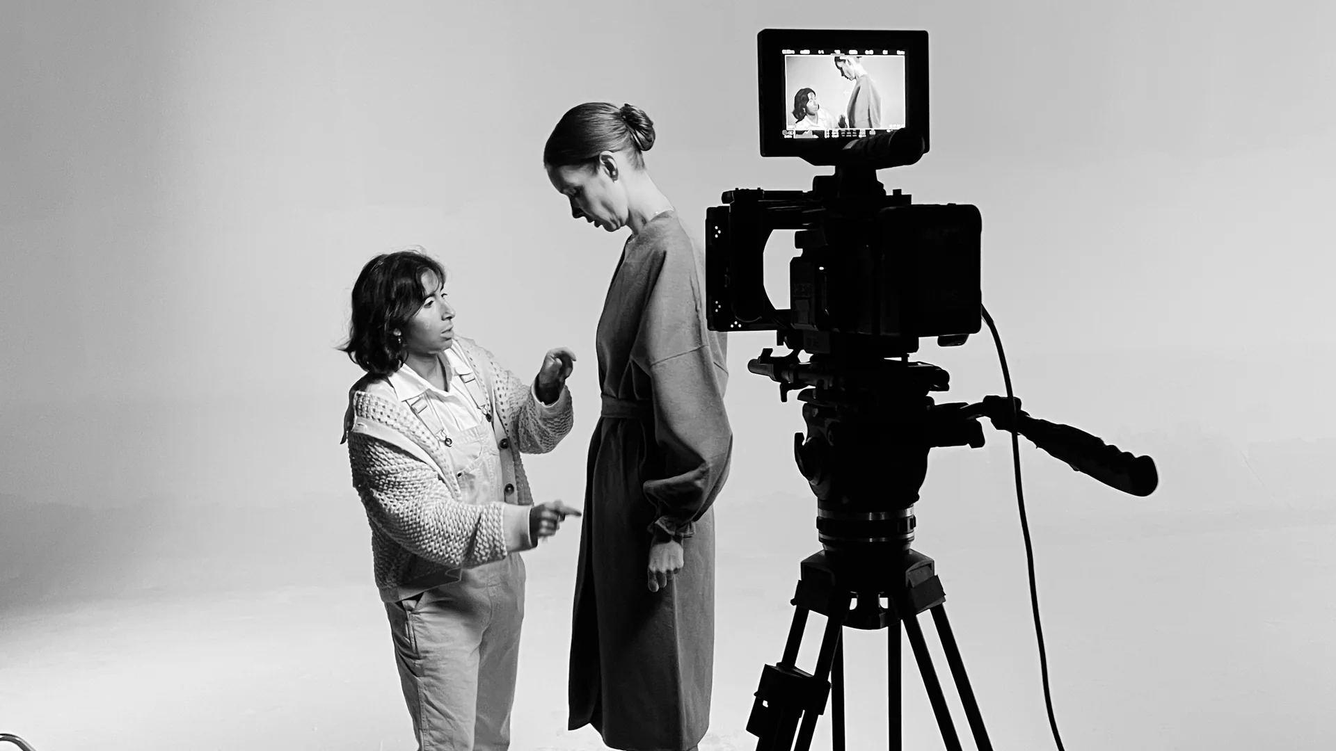 What a Professional Brand Photography Shoot Includes 1 Director styling a model on the white cyc beside the camera during a brand photography shoot at C&I Studios