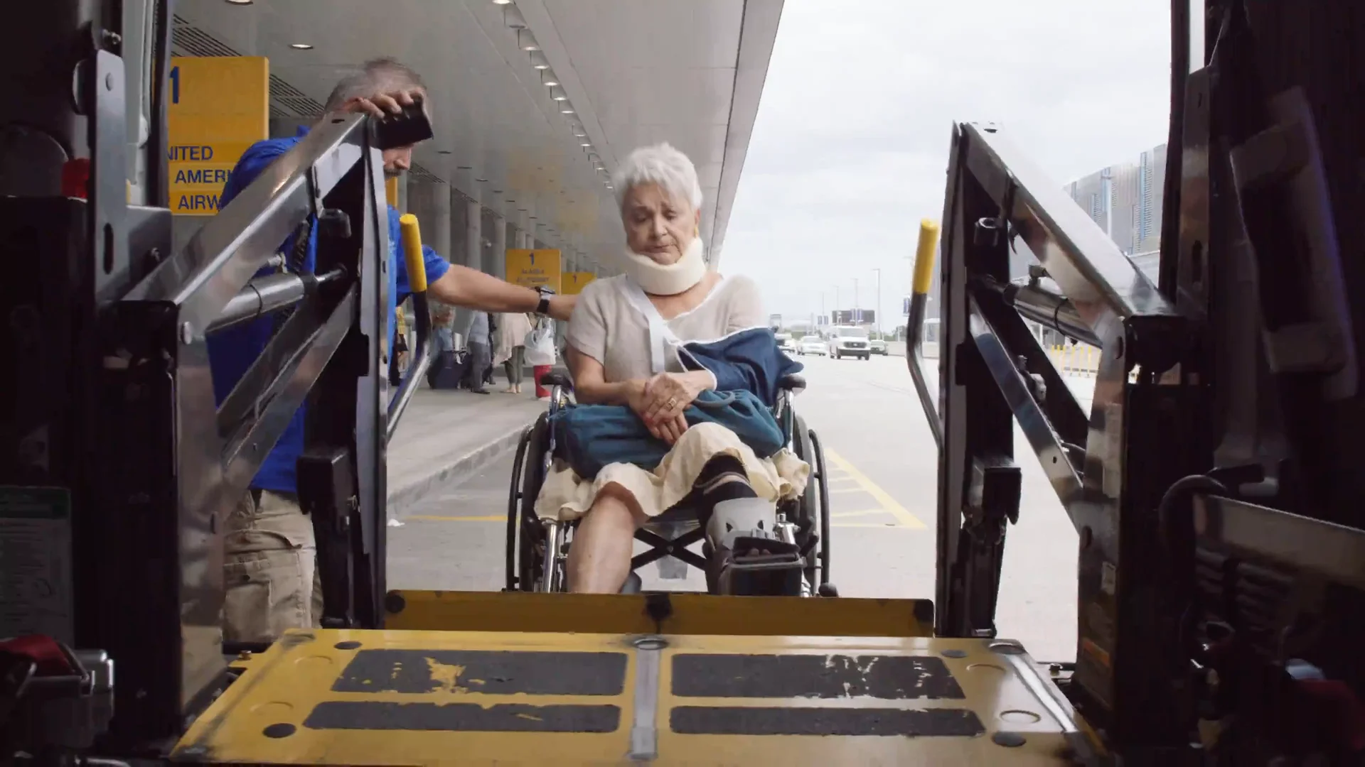 Patient in a wheelchair on a van lift at the airport curb