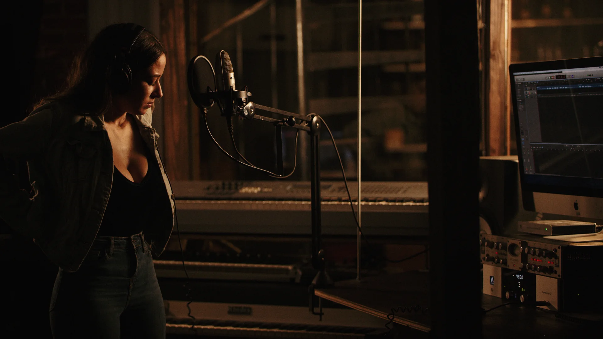 What a Music Video Production Budget Covers 1 Artist recording vocals at the mic in a dimly lit studio during a music video shoot by C&I Studios